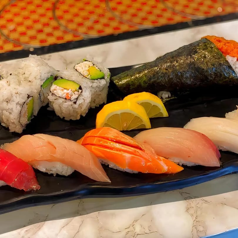 A black platter filled with various Miyozen sushi, including rolls, nigiri, and a hand roll.