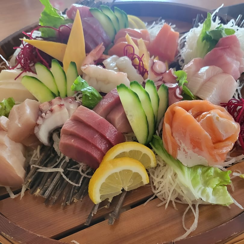 A large platter of Miyozen sashimi with various fish, octopus, shrimp, cucumber, and lemon slices.