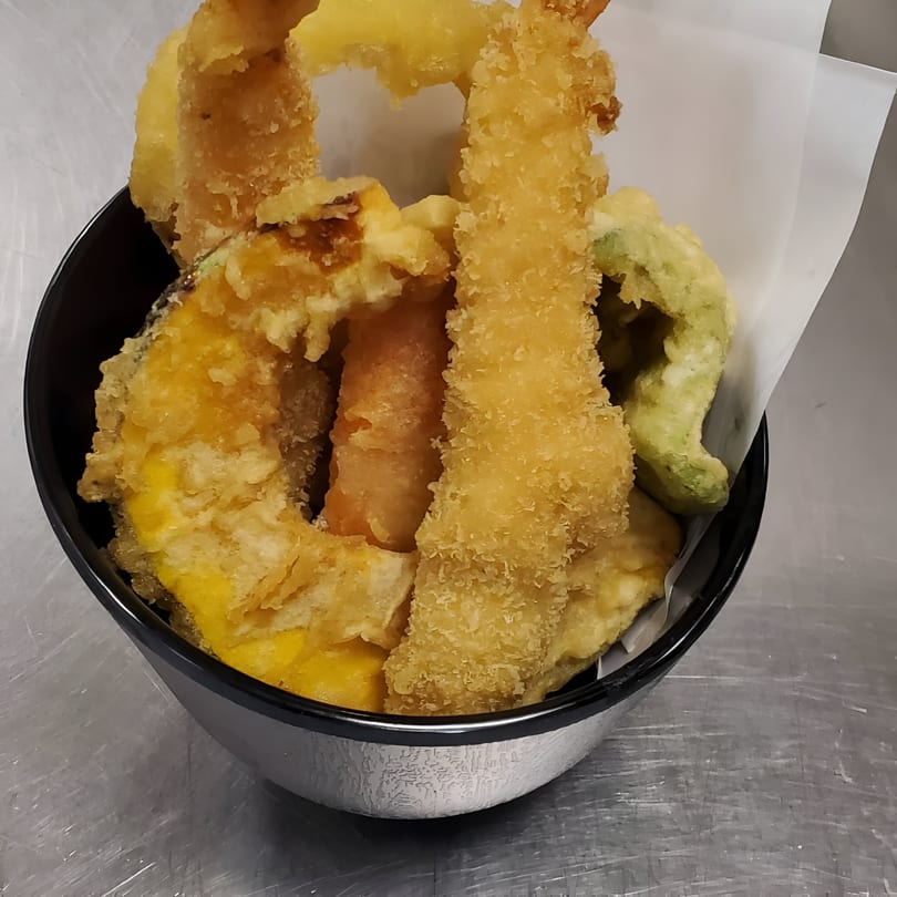 A black bowl filled with golden-brown Miyozen tempura, including shrimp, pumpkin, and green vegetables.
